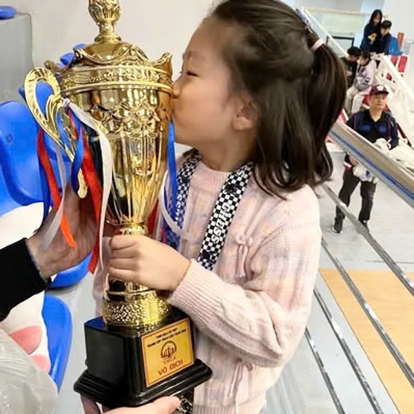 Bé Cam ôm chiếc cup vô địch